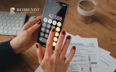 Dłonie liczą kwotę 42 588 na smartfonie przy biurku z dokumentami i kawą.