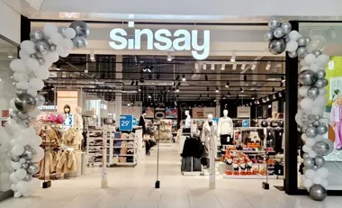 Wejście do sklepu Sinsay ozdobione łukiem z białych i srebrnych balonów.