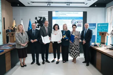 Grupa osób w sali konferencyjnej pozuje do zdjęcia po podpisaniu dokumentów dotyczących efektywności energetycznej w obszarze metropolitalnym Gdańska.