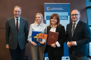 Cztery osoby pozują podczas uroczystości wręczenia dokumentów w siedzibie Urzędu Marszałkowskiego Województwa Pomorskiego.